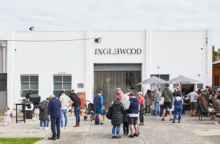 The exterior of Inglewood roastery a white brick building with people lining up out front.